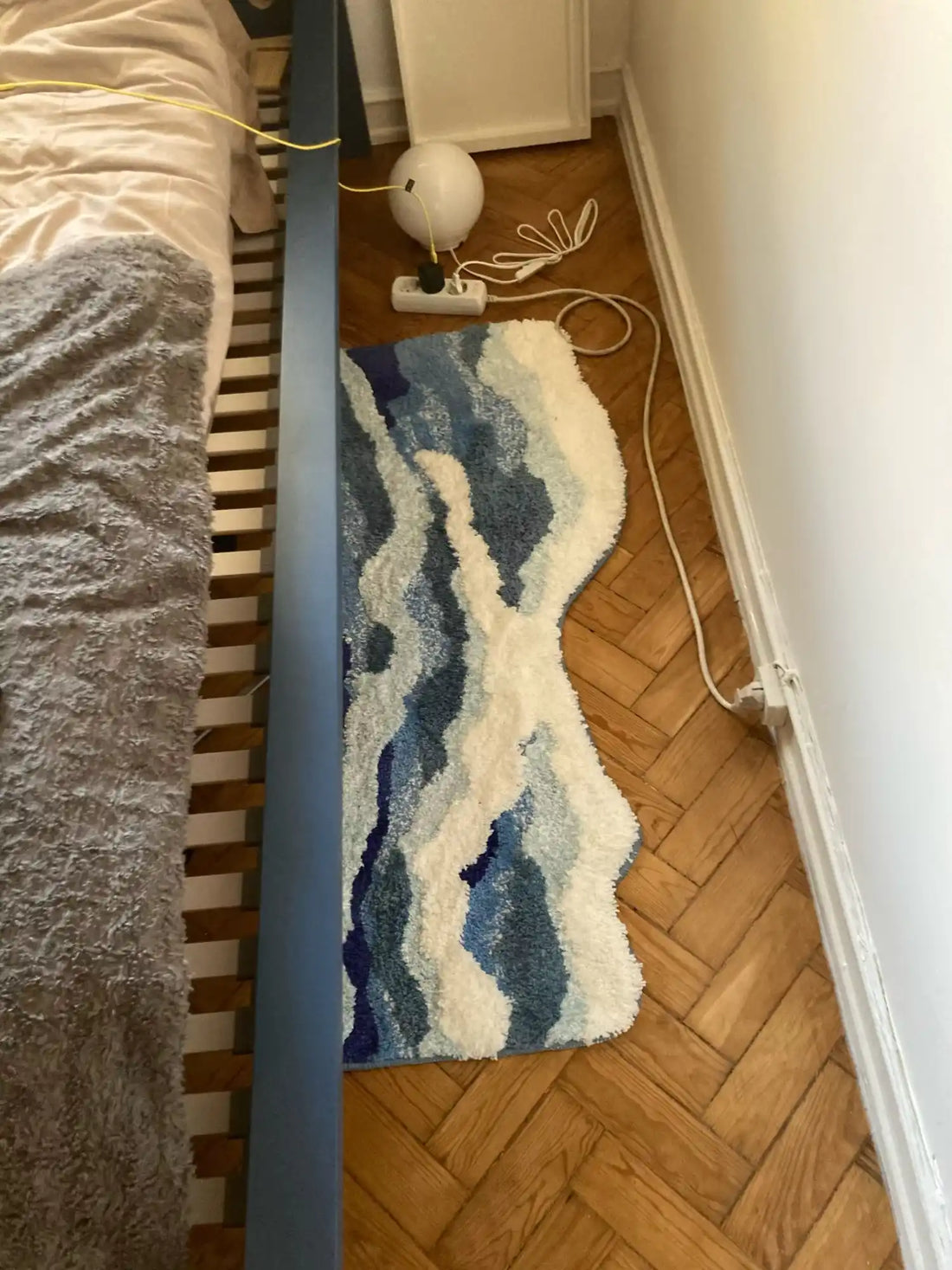 Un tapis de bain bleu et blanc à motif de vagues avec une forme irrégulière.