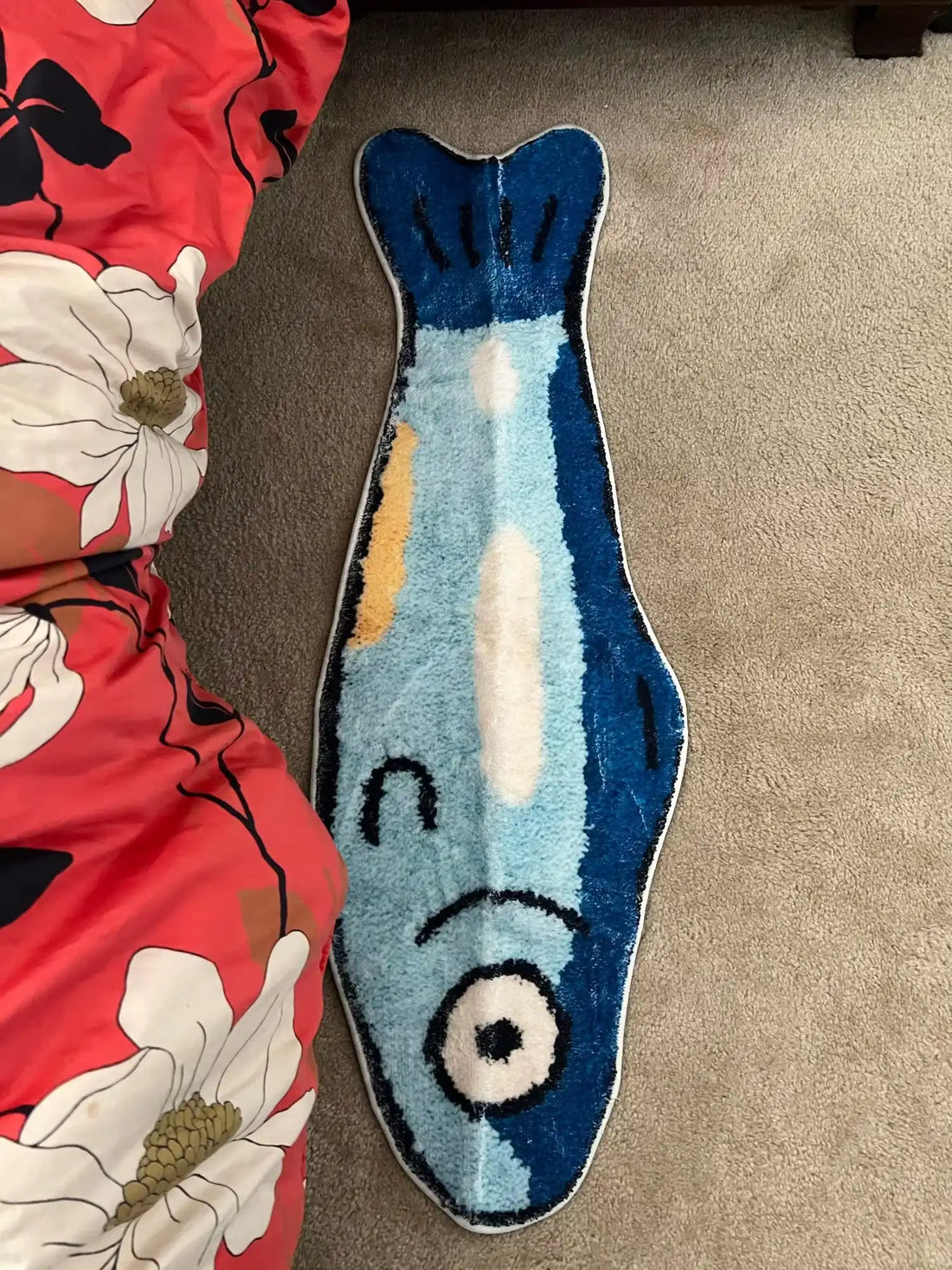 Moumoute de bain en forme de poisson bleu avec un ventre blanc, une nageoire jaune et un visage de dessin animé.
