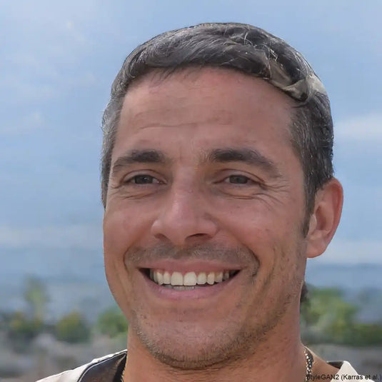 Homme souriant avec des cheveux courts et grisonnants, et un teint clair.