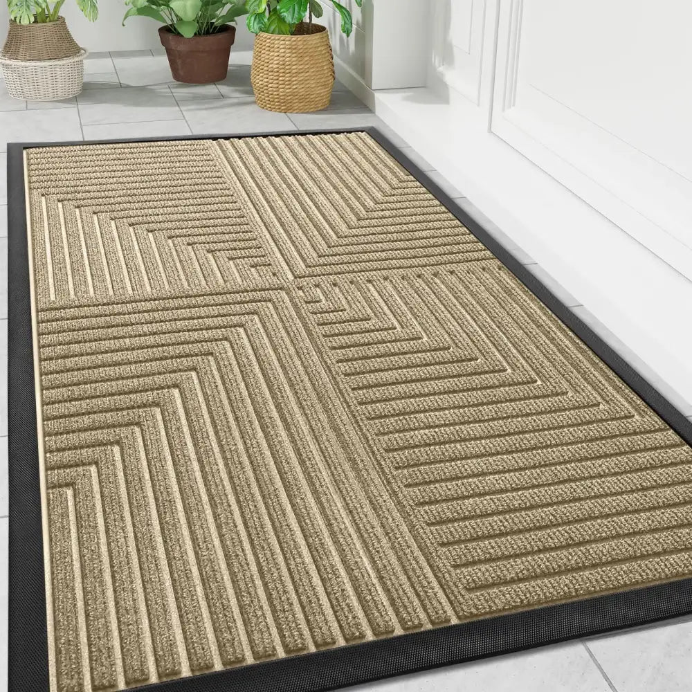 Paillasson beige à motif géométrique avec bordure noire, surface texturée ressemblant à de la sisal ou du jute.