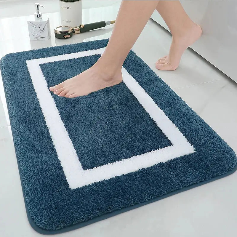Tapis de bain bleu marine avec bordure blanche et motif carré, matériau moelleux.