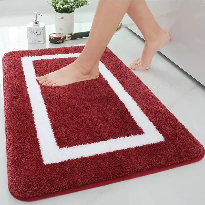 Tapis de bain rouge avec bordure blanche et design rectangulaire, fabriqué en matériau microfibre.