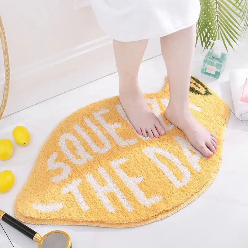 Tapis de bain jaune à thème agrumes avec texte blanc et surface texturée.