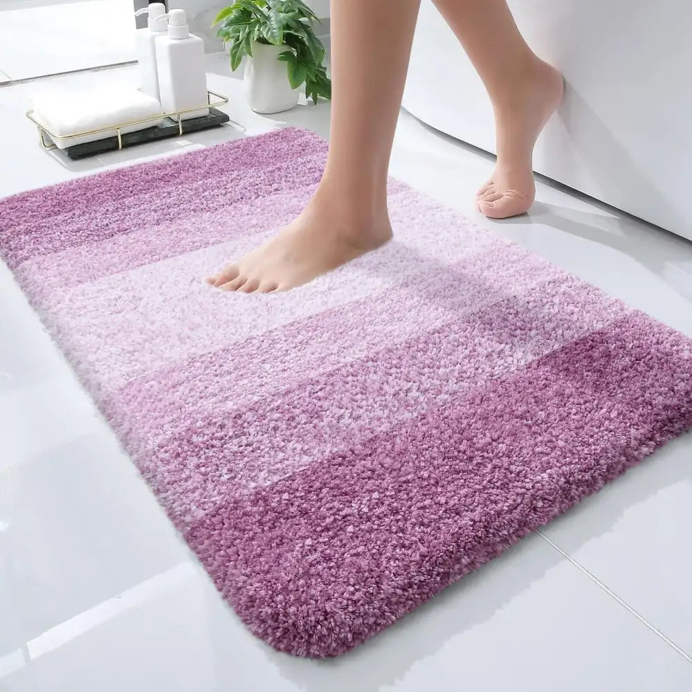 Un tapis de bain moelleux à dégradé violet avec une texture douce et pelucheuse et des bords arrondis.