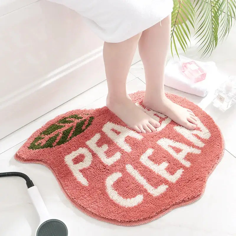 Tapis de bain de couleur pêche avec le texte « pea clean » et un motif de feuille, fabriqué en microfibre douce.