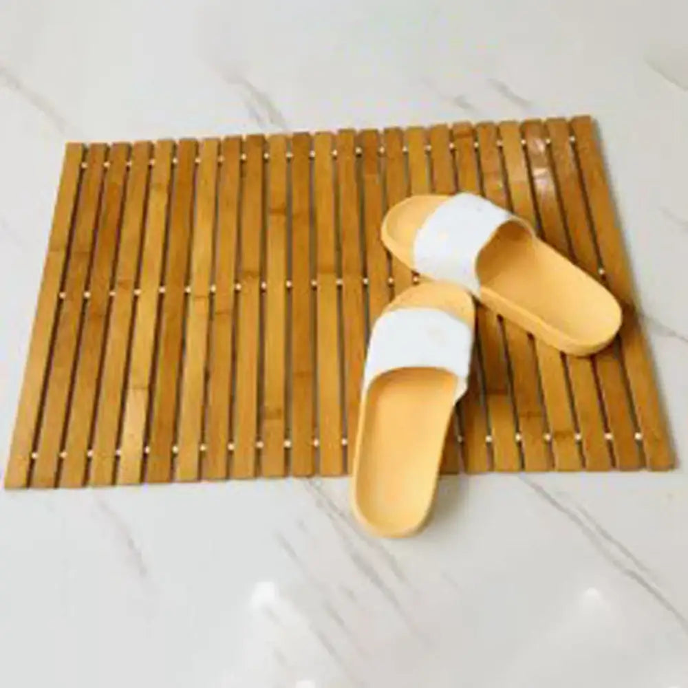 Une paire de sandales à enfiler de couleur jaune clair et blanche reposant sur un tapis en bambou.