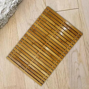 Tapis de bain en bambou rectangulaire avec lattes brun doré clair et petites fixations métalliques.