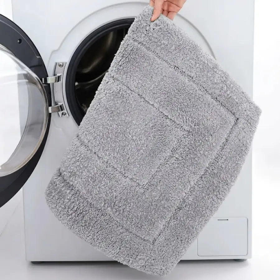 Tapis de bain gris perle en peluche avec texture bouclée et bordure subtilement cousue gris clair