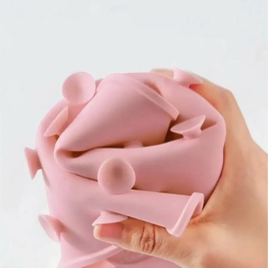 Poignée ventouse en silicone rose avec des protubérances arrondies.