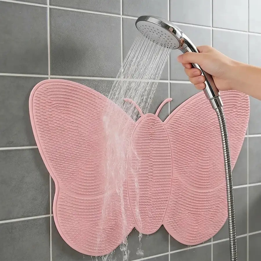 Tapis de douche rose en forme de papillon avec surface texturée.
