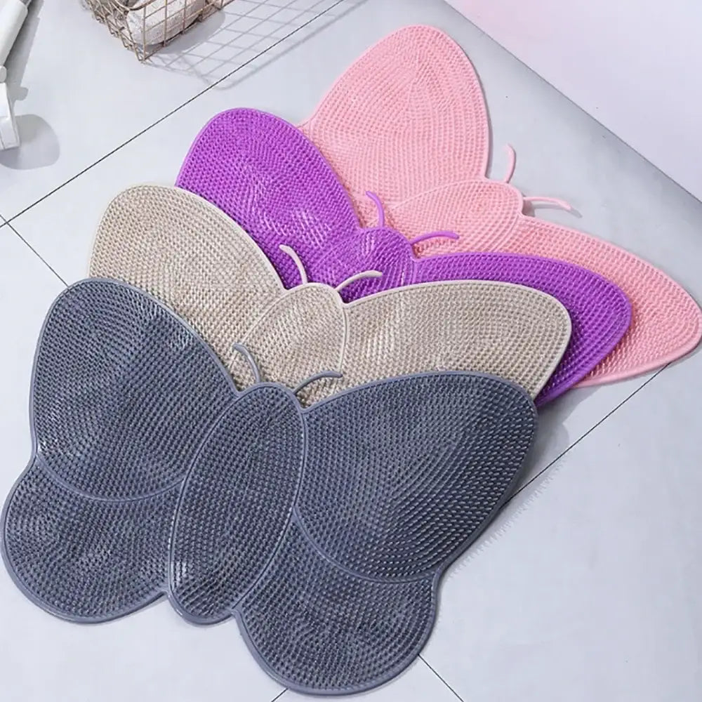 Tapis de bain en forme de papillon aux couleurs pastel en rose doux, violet, beige et gris avec une surface en silicone texturée.
