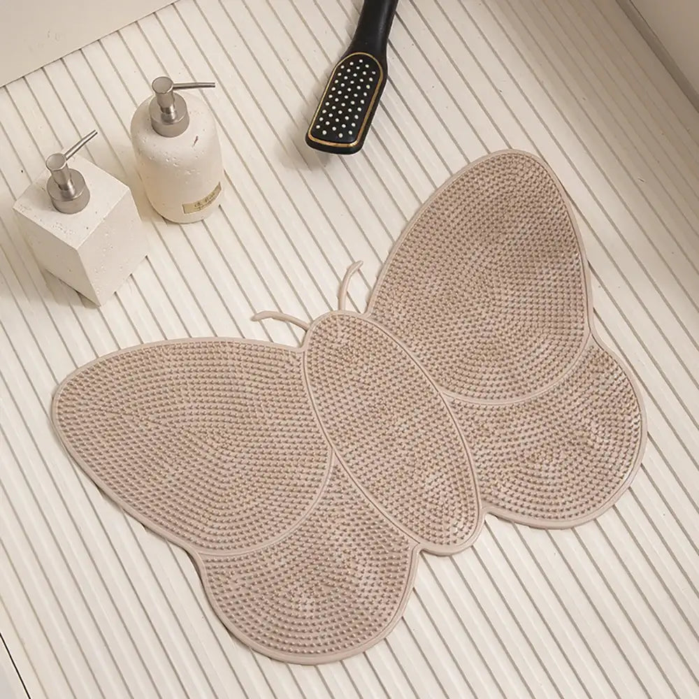 Tapis de bain en forme de papillon beige avec surface texturée antidérapante.