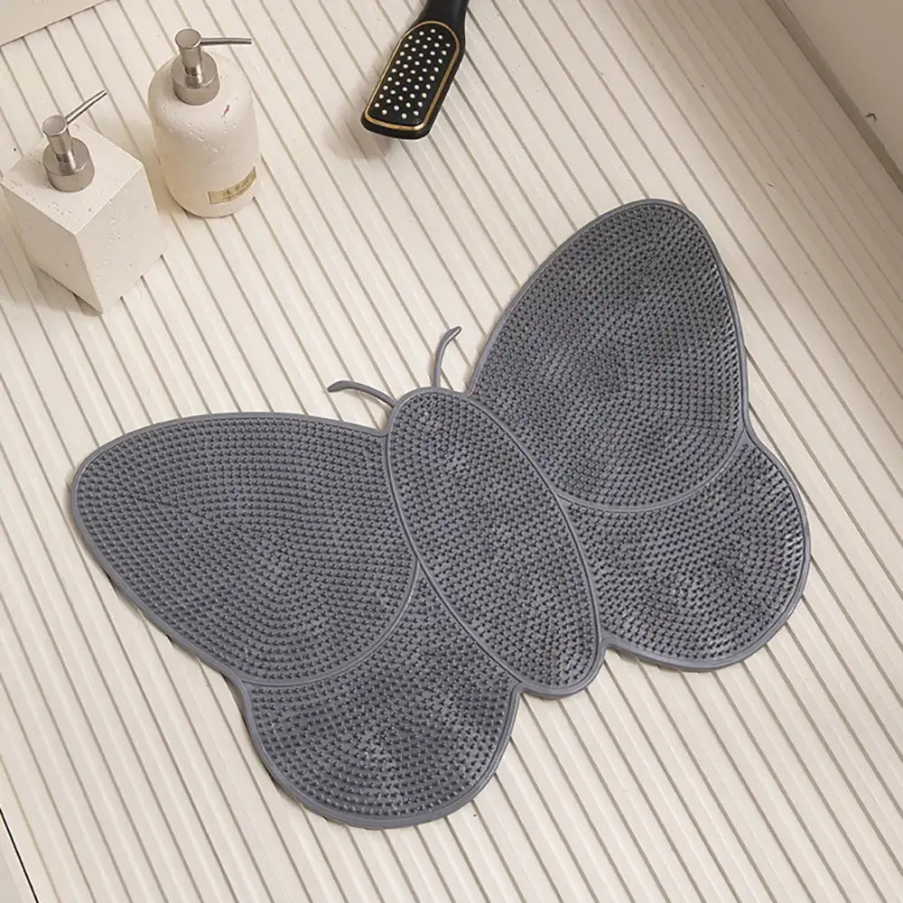 Tapis de bain gris en forme de papillon avec une surface texturée antidérapante.