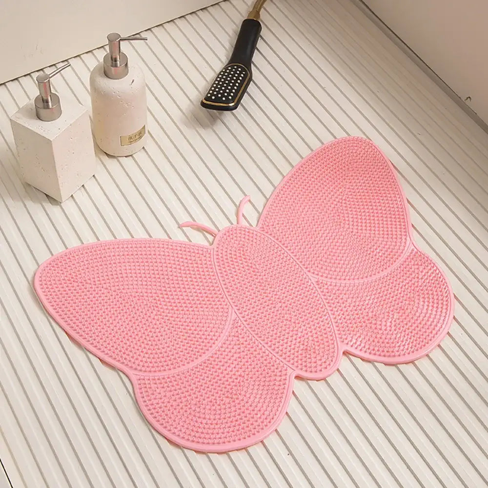 Tapis de bain en forme de papillon rose avec une surface texturée antidérapante.