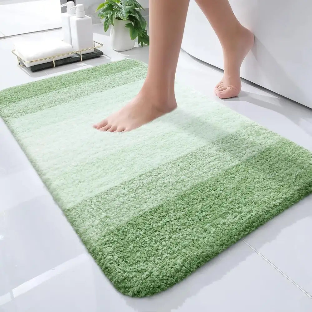 Un tapis de bain doux et moelleux avec des rayures horizontales dans diverses nuances de vert.