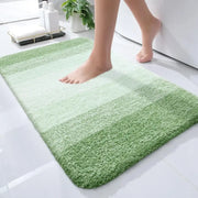 Un tapis de bain doux et moelleux avec des rayures horizontales dans diverses nuances de vert.