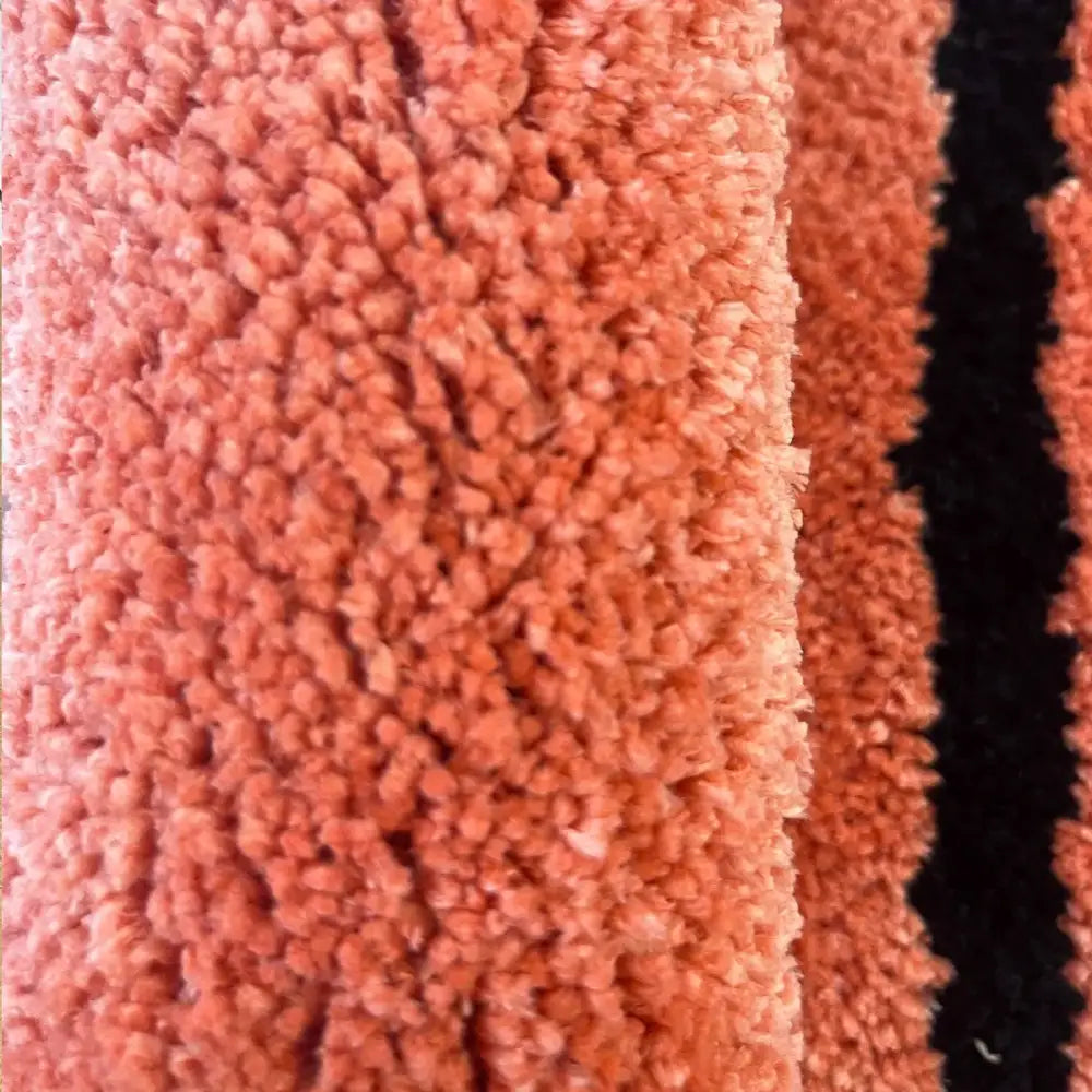 Tapis de bain en corail duveteux avec design à rayures noires.