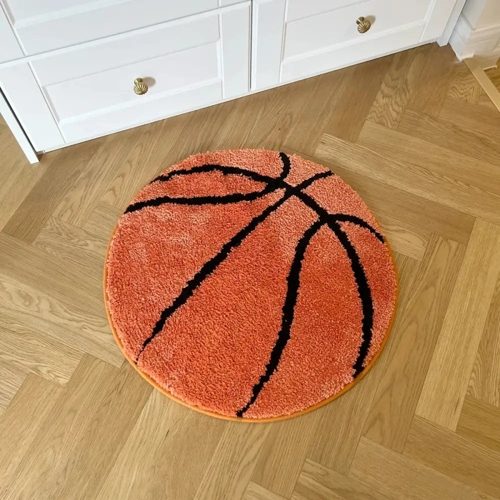 Tapis orange en forme de ballon de basket avec des lignes noires, matériau moelleux.