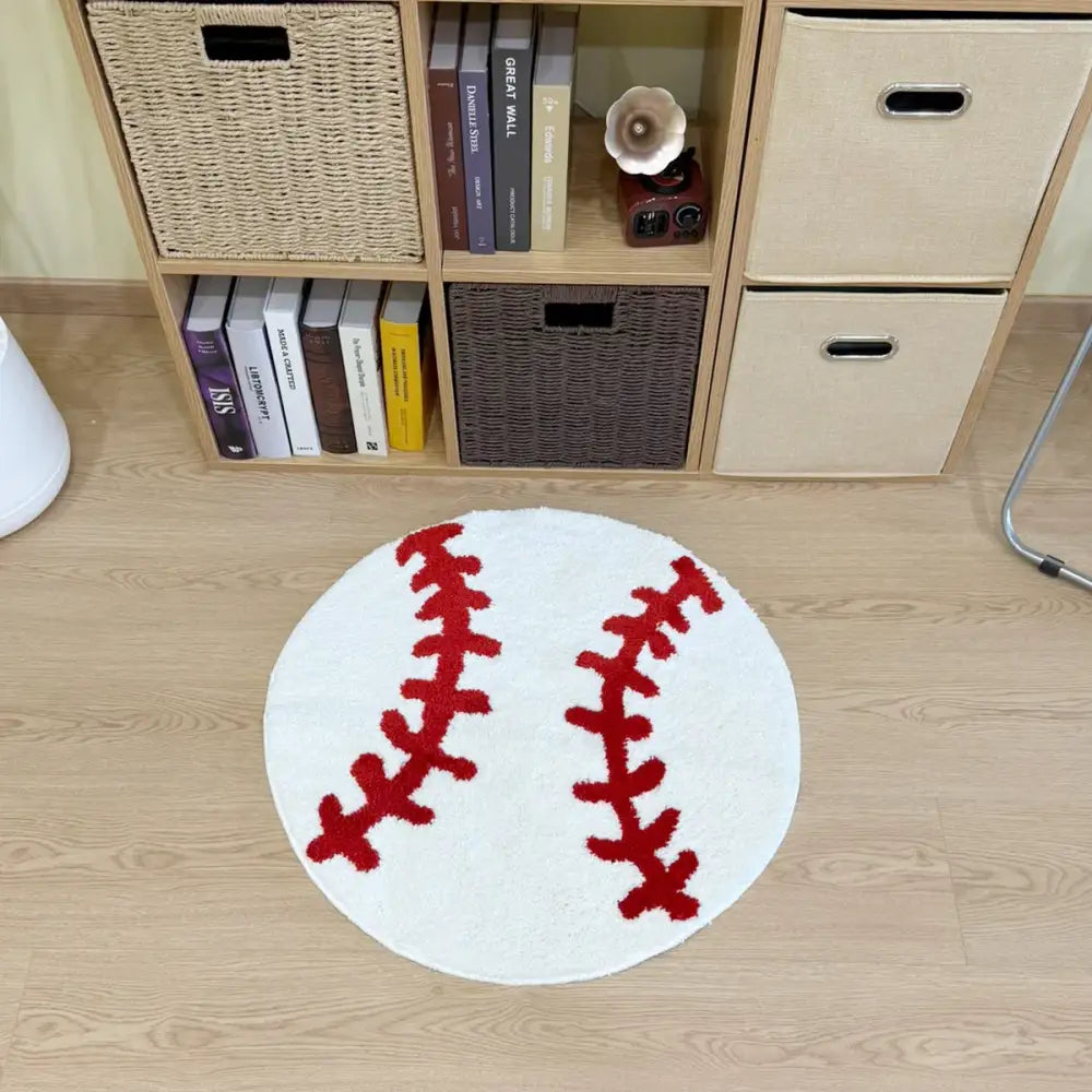 Tapis blanc en forme de balle de baseball avec un motif de coutures rouges, probablement fabriqué en matériau moelleux.