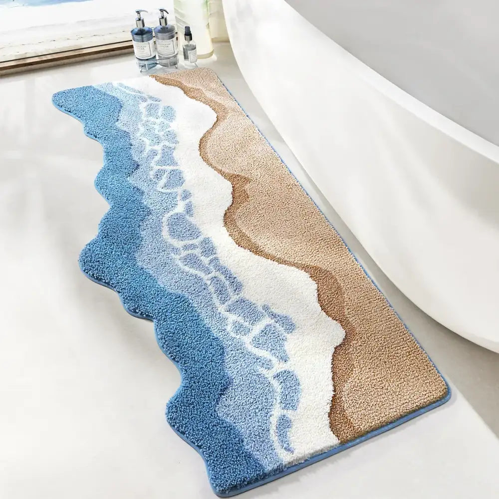 Tapis de bain bleu et beige avec motif de vague océanique texturé, probablement fabriqué en microfibre ou matériau similaire.