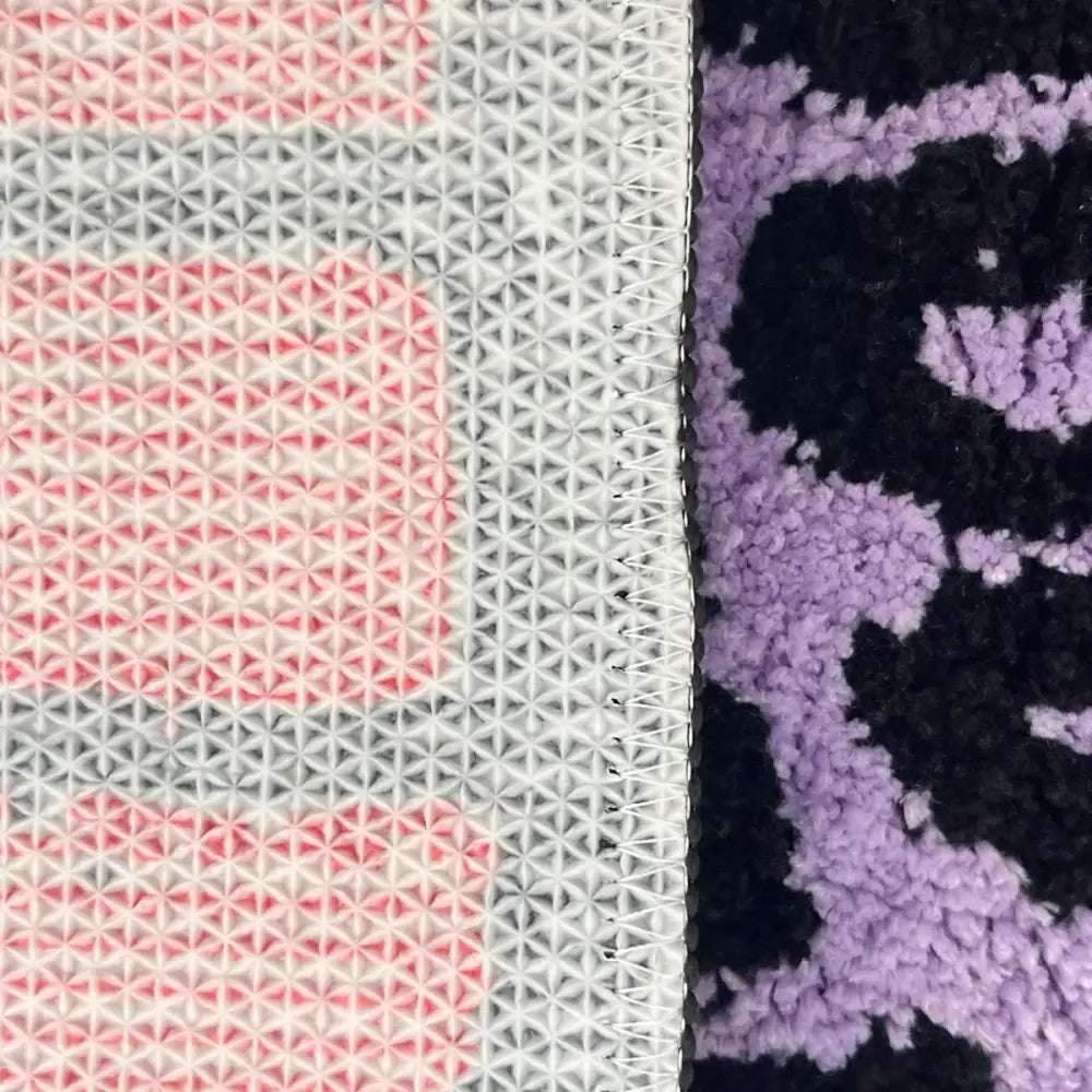 Tapis à motif géométrique rose et gris avec dos blanc.