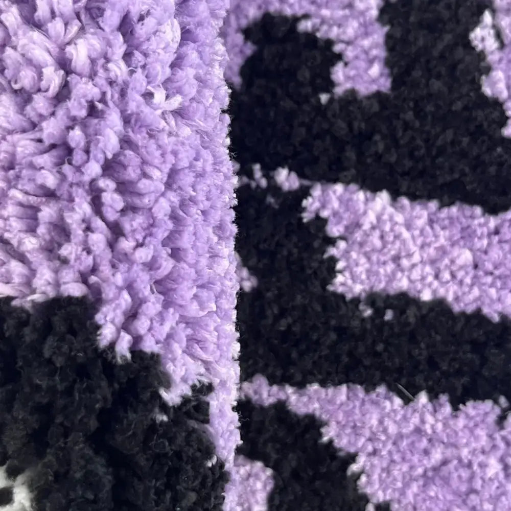 Couverture en chenille lavande et noire avec un motif géométrique.
