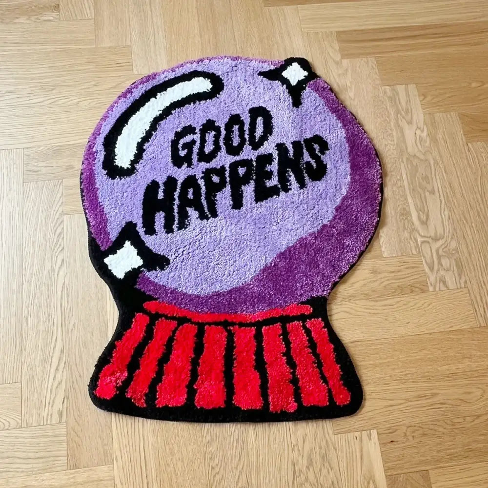 Tapis de bain boule de cristal violette avec le texte « good happens » en noir et blanc.