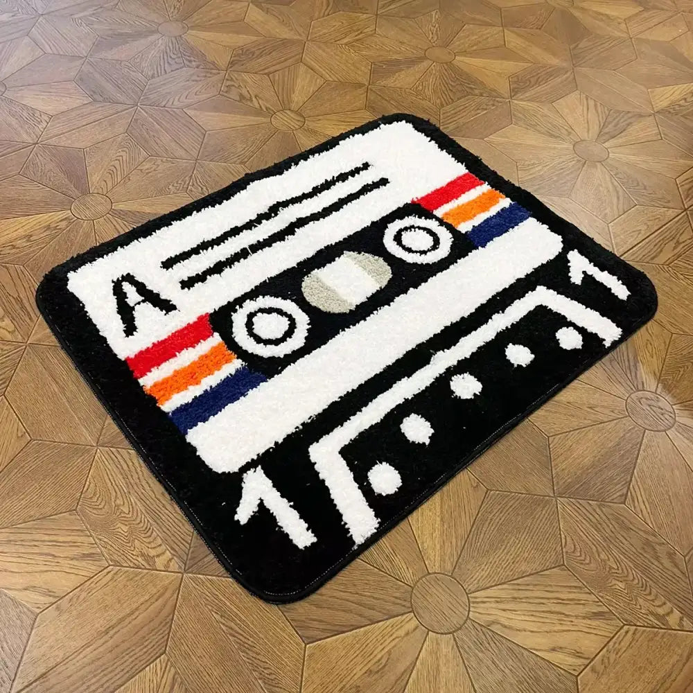 Tapis cassette pelucheux en forme de cassette noir blanc et multicolore avec surface texturée et support caoutchouc
