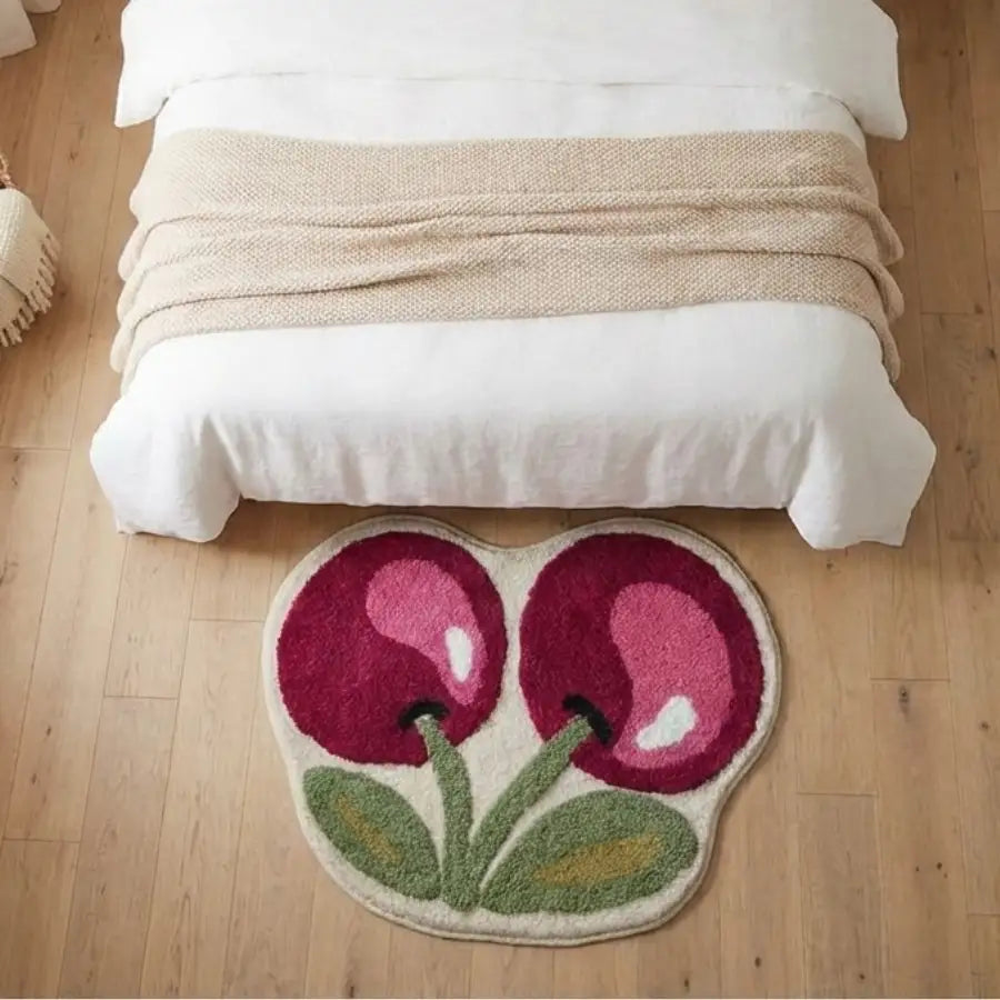 Tapis en forme de cerise avec des accents rouges et verts vibrants, fabriqué en matériau moelleux.