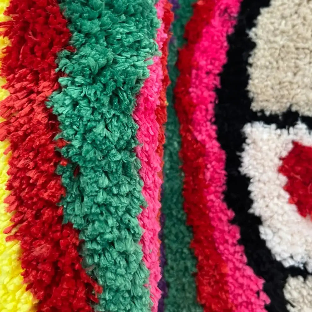 Tapis shaggy multicolore avec des rayures vives et des motifs circulaires, probablement fabriqué en polyester ou en nylon.