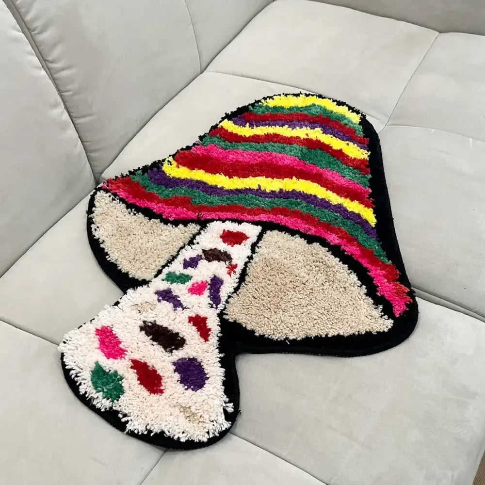 Tapis de bain en forme de champignon multicolore avec chapeau rayé et tige tachetée, fabriqué en matériau moelleux.