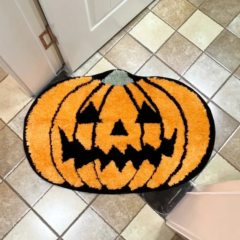 Tapis de bain citrouille d’Halloween orange avec rayures noires et design de visage, probablement fait de matériau moelleux.