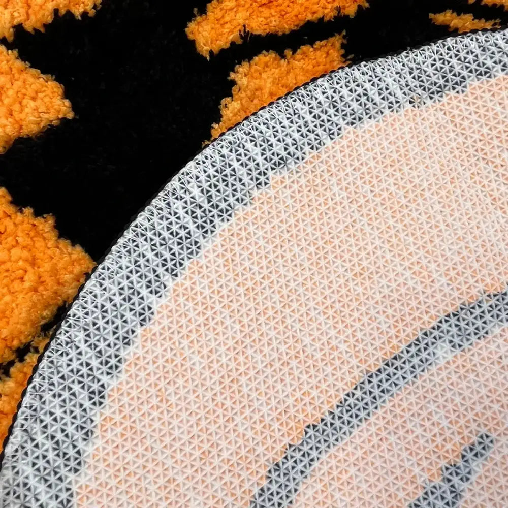 Tapis en peluche orange et noir avec motif géométrique sur le dos.