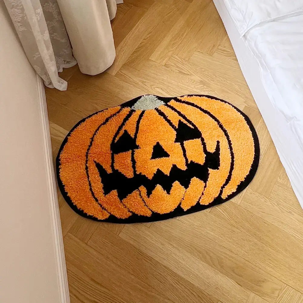Tapis de bain en forme de citrouille orange et noir avec un design de visage de lanterne-jack-o’-lantern.