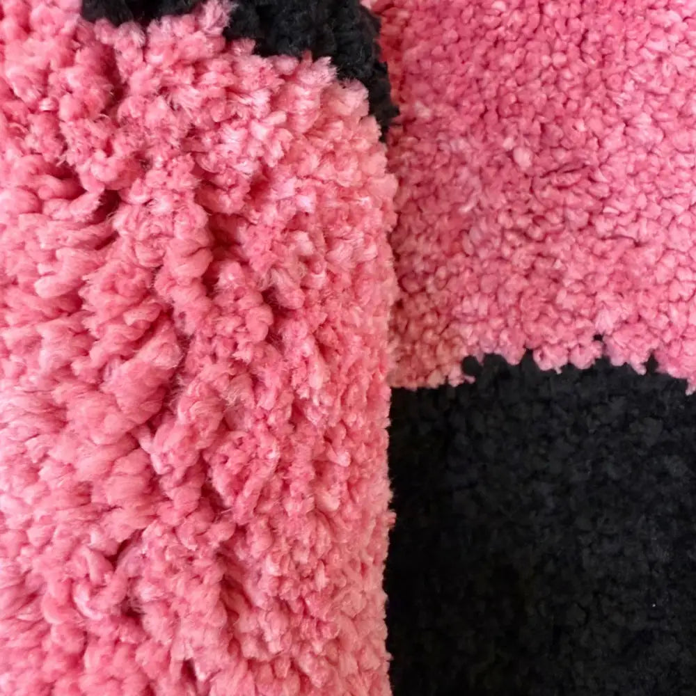 Pantoufles roses et noires duveteuses avec une toison texturée.