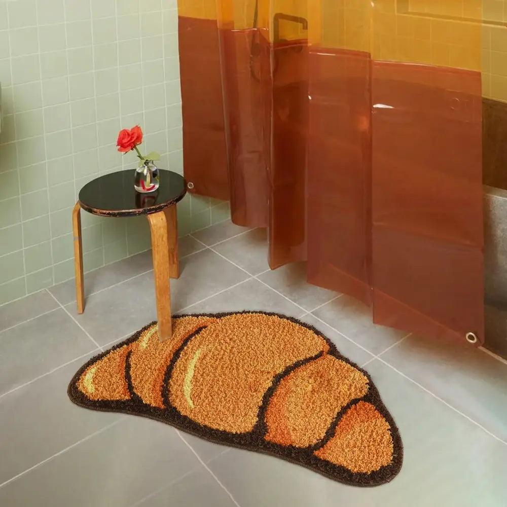 Tapis de bain en forme de croissant aux nuances doré-brun et brun foncé, texture moelleuse, probablement fabriqué en microfibre ou matériau similaire.