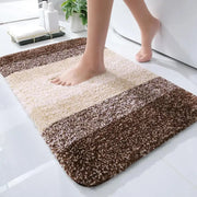 Un tapis de bain moelleux à rayures aux tons crème et marron avec une surface douce et texturée.