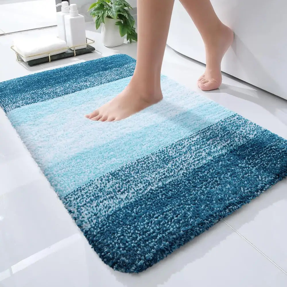 Un tapis de bain moelleux à dégradé bleu avec une texture douce et duveteuse et une transition du bleu marine profond à l’aqua clair.