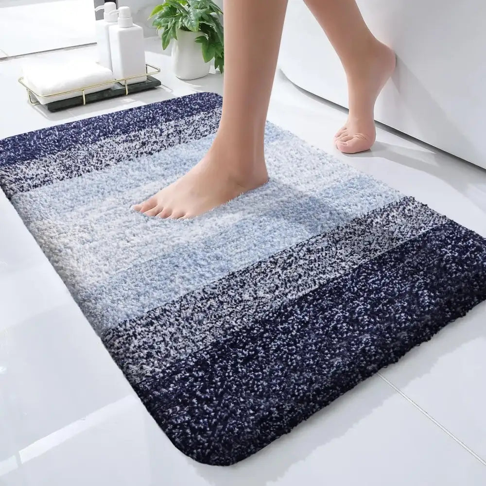 Un tapis de bain moelleux à dégradé bleu avec une surface texturée douce et des bords arrondis.