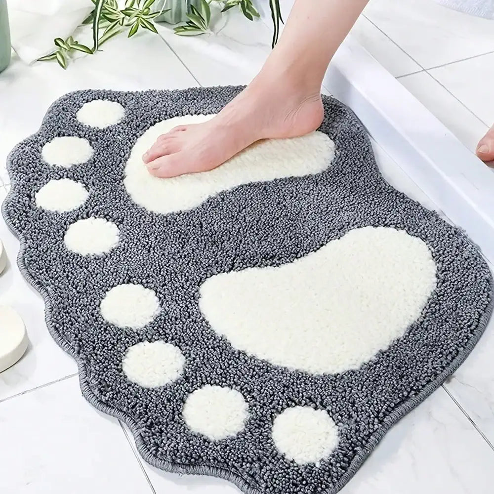 Tapis de bain à empreinte de patte grise avec accents blancs et surface texturée, probablement fabriqué en microfibre ou matériau similaire.