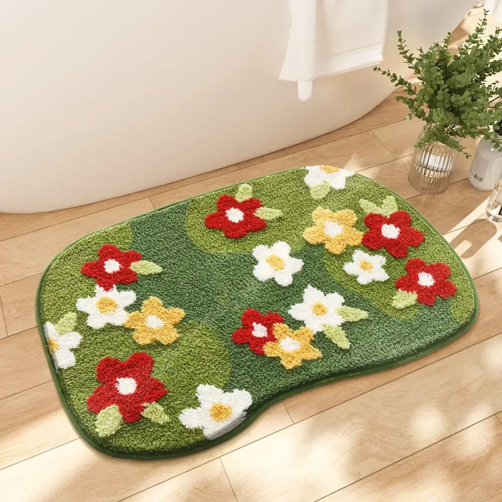 Tapis de bain floral vert avec des fleurs rouges, jaunes et blanches sur une surface texturée.