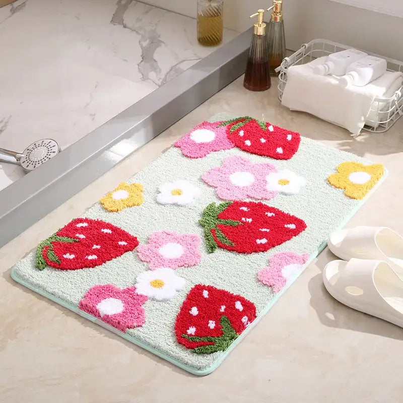 Tapis de bain fraise avec des fraises rouges vibrantes et des fleurs blanches sur un fond vert clair, fabriqué en microfibre douce.