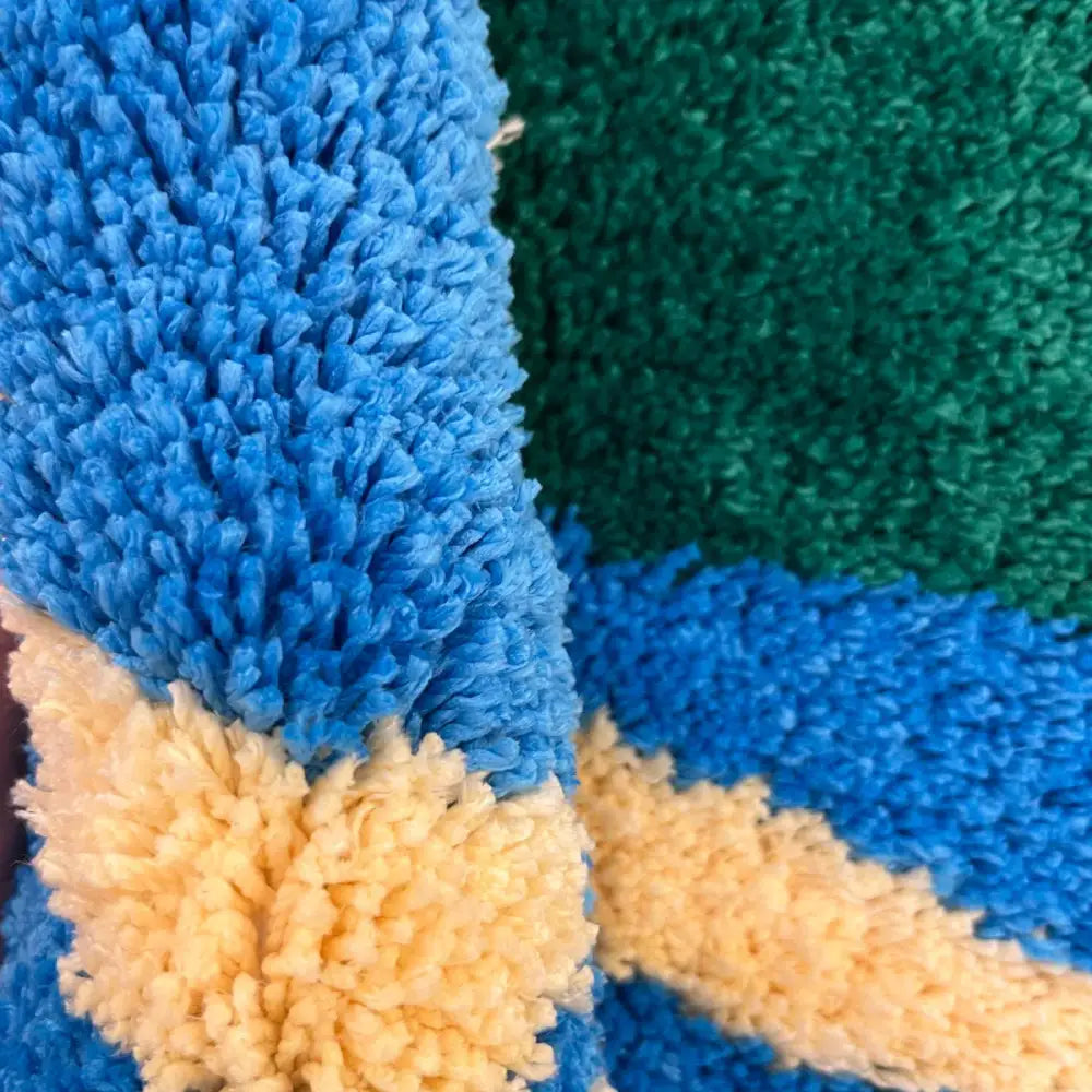 Tissu moelleux bleu, vert et jaune avec une surface texturée et duveteuse.