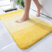 Un tapis de bain moelleux à dégradé jaune avec une texture douce et duveteuse et des bords arrondis.