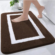 Tapis de bain marron et blanc avec un design rectangulaire, matériau doux pour le confort.