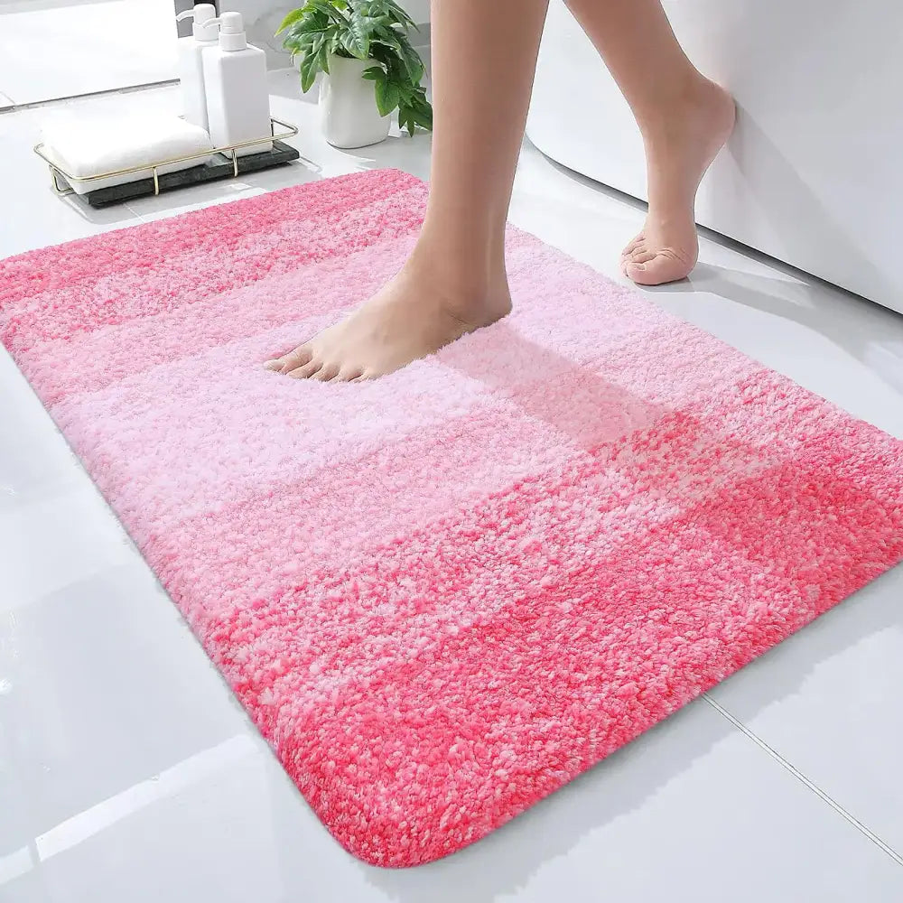 Un tapis de bain rose dégradé moelleux avec une texture douce et duveteuse et des bords arrondis.