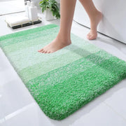Un tapis de bain moelleux à dégradé vert avec une texture douce et bouclée, et des bords arrondis.