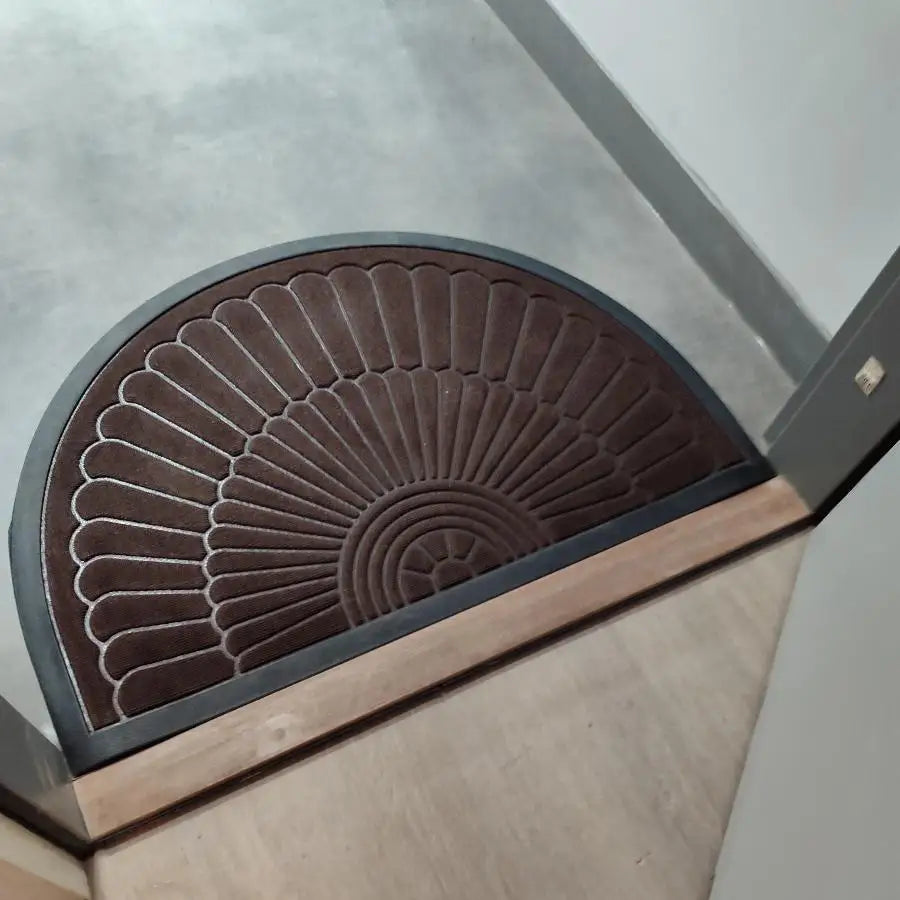 Paillasson semi-circulaire marron avec un motif en éventail et une bordure sombre.