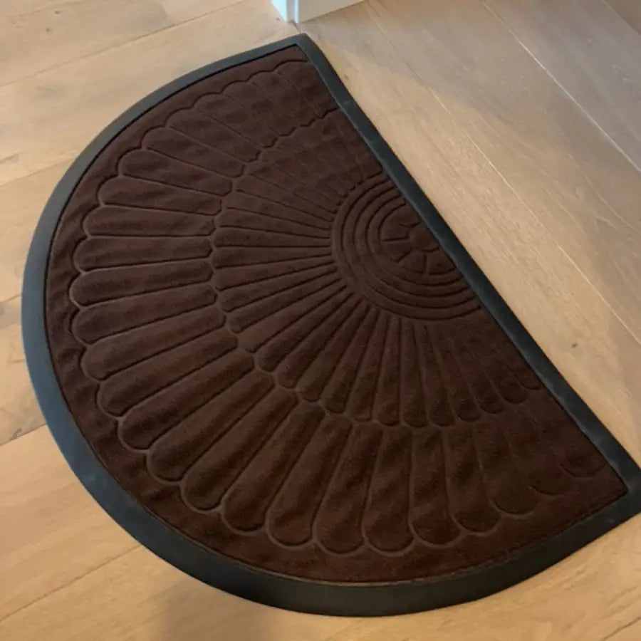 Paillasson semi-circulaire marron avec un motif texturé en rayons de soleil et bordure en caoutchouc noir.
