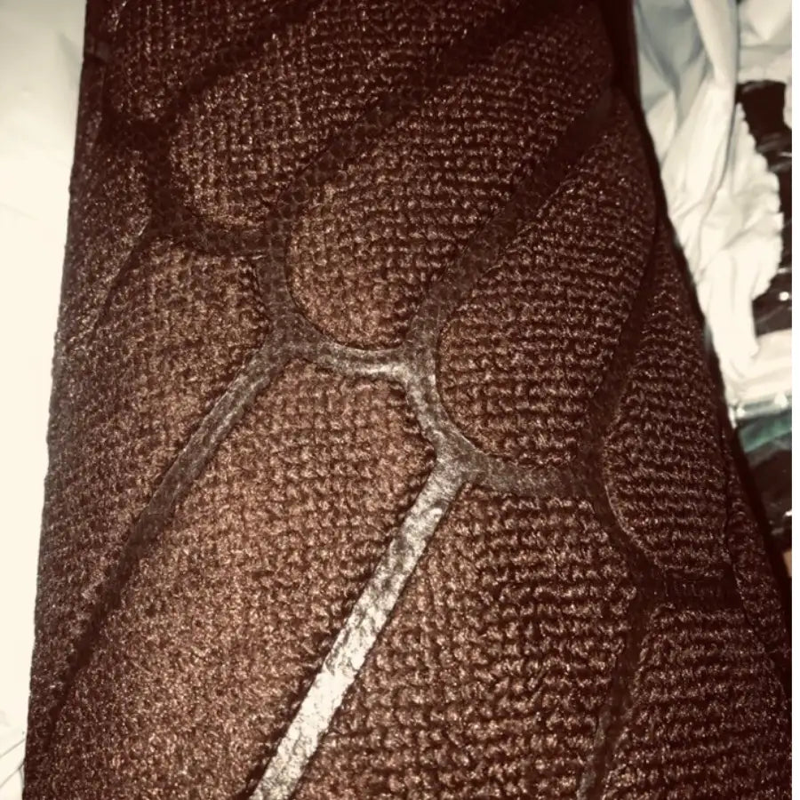 Tissu matelassé marron foncé avec un motif texturé tissé et des lignes cousues formant un design géométrique complexe.